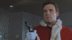 A still from the film "Rendeer Games" featuring Ben Affleck dressed as Santa Claus holding a gun