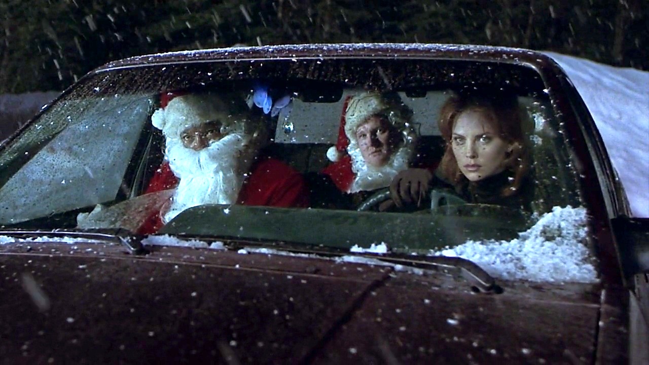 A still from the film "Rendeer Games" featuring Clarence Williams III, Donal Logue and Charlize Theron sitting in a car