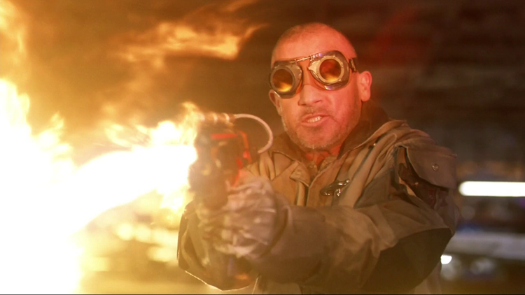 Heat Wave (Dominic Purcell) fires a flamethrower at an unseen opponent in a still from the CW show "Legends of Tomorrow."