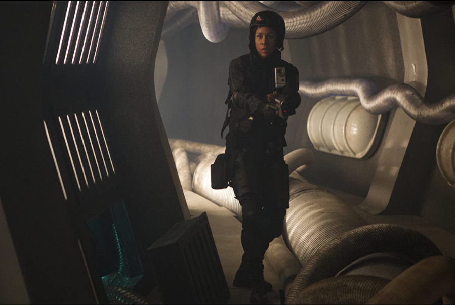 Zawe Ashton as Journey Blue, a space ranger holding a futuristic gun in a still from the BBC show "Doctor Who".
