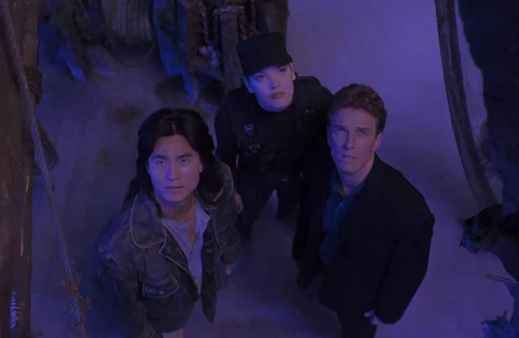Liu Kang (Robin Shou), Sonya Blade (Bridgette Wilson), and Johnny Cage (Linden Ashby) stare up at incoming danger in a still from the 1995 film 