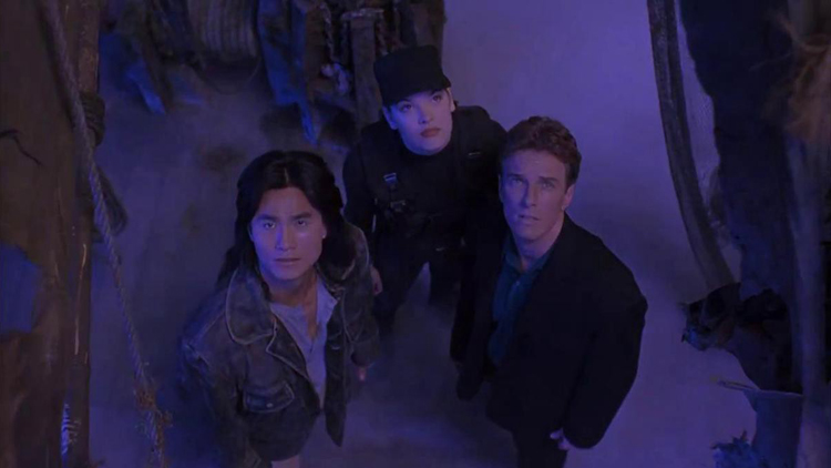 Liu Kang (Robin Shou), Sonya Blade (Bridgette Wilson), and Johnny Cage (Linden Ashby) stare up at incoming danger in a still from the 1995 film "Mortal Kombat."