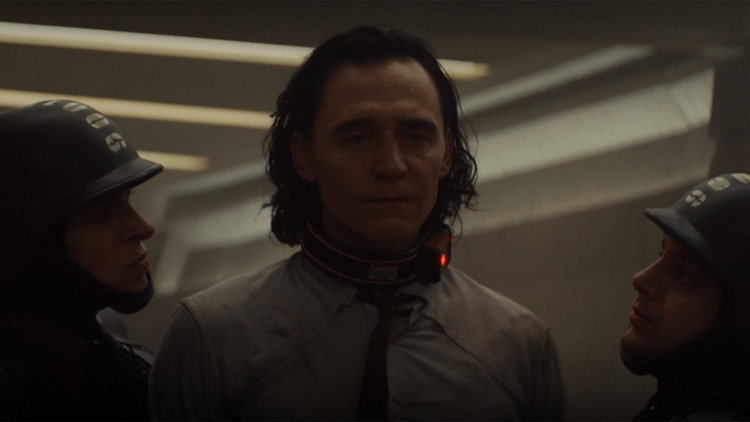 Loki (Tom Hiddleston) offers no resistance to his TVA guards in a still from the Disney+ series "Loki."