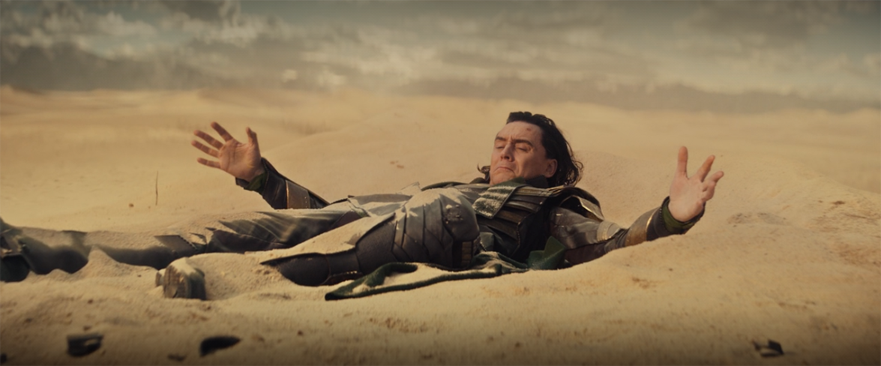 Loki (Tom Hiddleston) ends up in the sand of the Gobi Desert after escaping the Avengers in a still from the Disney+ series "Loki."