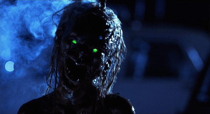 A demon with glowing green eyes threatens the inhabitants of an old church turned hotel a still from "Tales from the Crypt: Demon Knight."