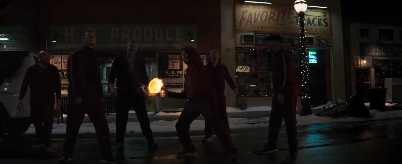 A group of tracksuited thugs throw a Molotov cocktail at Hawkeye in a still from the trailer for "Hawkeye" on Disney+.