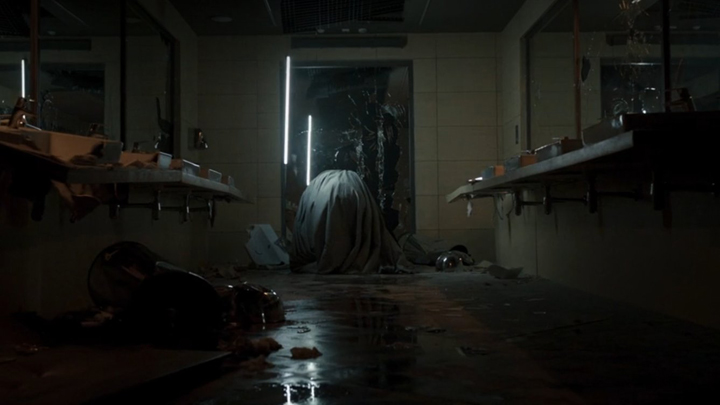Moon Knight kneels is a dirty bathroom punching an unseen enemy in a still from the upcoming Disney+ show "Moon Knight."