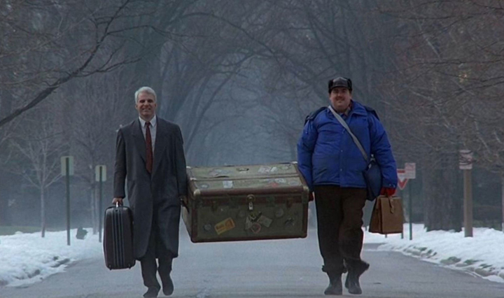 Neal Page (Steve Martin) helps Del Griffith (John Candy) carry his oversized trunk in a still from "Planes, Trains and Automobiles."