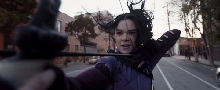 Kate Bishop (Hailee Steinfeld) fend off the Tracksuit Mafia from a moving car in a still from the Disney+ series "Hawkeye."