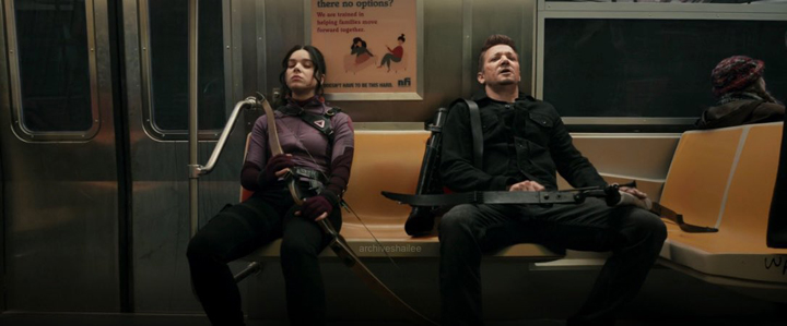 Kate Bishop (Hailee Steinfeld) and Clint Barton (Jeremy Renner) ride a subway home after escaping from the Tracksuit Mafia in a still from the Disney+ series "Hawkeye."