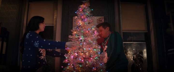 Kate Bishop (Hailee Steinfeld) and Clint Barton) decorate a Christmas tree while wearing ugly sweaters in a still from the Disney+ series "Hawkeye."