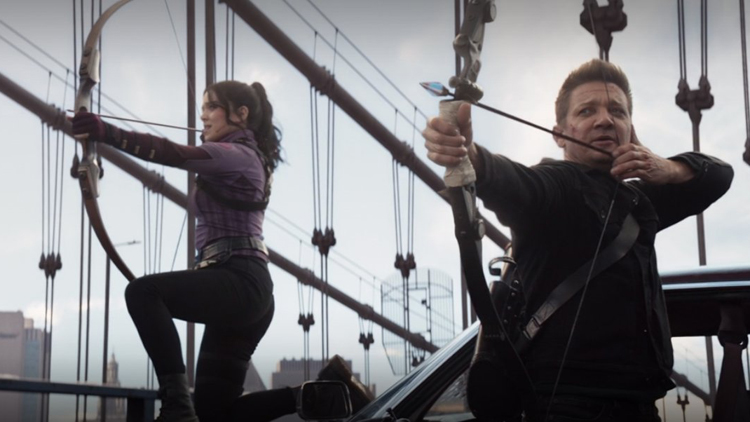Kate Bishop (Hailee Steinfeld) and Clint Barton (Jeremy Renner) ready arrows at the oncoming Tracksuit Mafia in a still from the Disney+ series "Hawkeye."