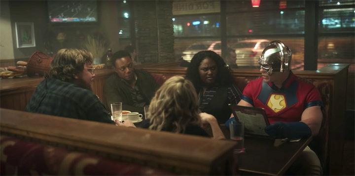 Economos (Steve Agee), Murn (Chukwudi Iwuji) Harcourt (Jennifer Holland), and Adebayo (Danielle Brooks) are embarrassed that Peacemaker (John Cena) showed up to the restaurant in his unifrom in a still from the HBOMax show "Peacemaker."