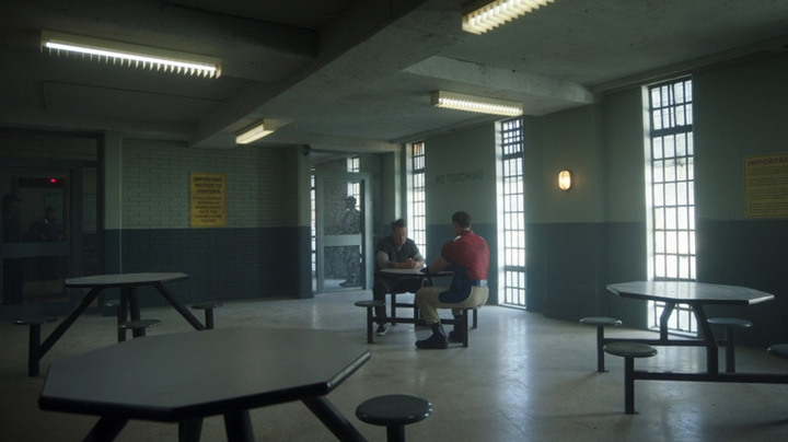August (Robert Patrick) and Peacemaker (John Cena) sit in a dank, empty room in the Evergreen prison in a still from HBOMax's "Peacemaker."