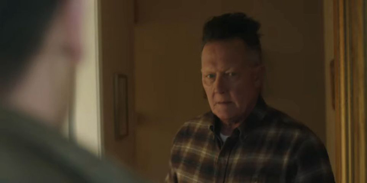 Auggie Smith (Robert Patrick) answers the door to find two cops on his porch in a still from the HBOMax show "Peacemaker."