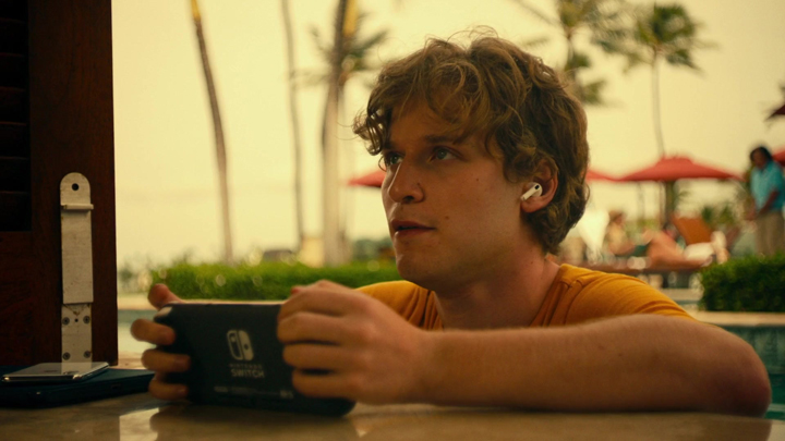Quinn Mossbacher (Fred Hechinger) plays a Nintendo Switch in a pool in a still from the HBO series "The White Lotus."