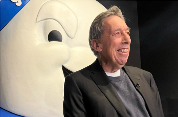 Ivan Reitman at the Alamo Drafthouse Theater sitting in front of a Stay Puf Marshmallow man statue.