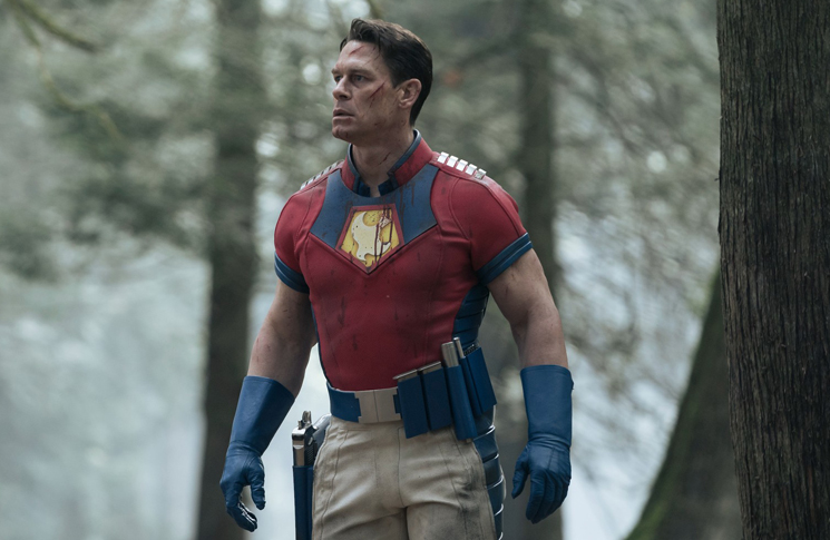 Peacemaker (John Cena) begins to hallucinate visions of his father in the woods in a still from the HBOMax series 