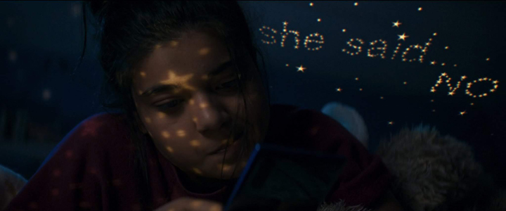 Kamala Khan (Iman Vellani) texts her friend Bruno some disappointing news as the message is displayed in light over her head in a still from the Disney+ series "Ms. Marvel."