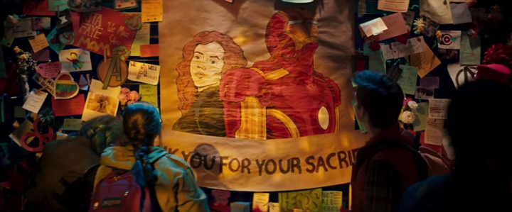 Kamala (Iman Vellani) and Bruno (Matt Lintz) look up at a remembrance wall for Black Widow and Iron Man in a still from the Disney+ series "Ms. Marvel."